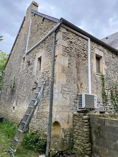 Pompe à chaleur installée sur le pignon d'une maison en pierre
